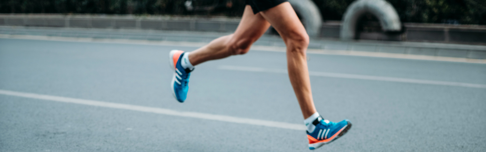 person running in blue adidas shoes on the road, perhaps during a marathon