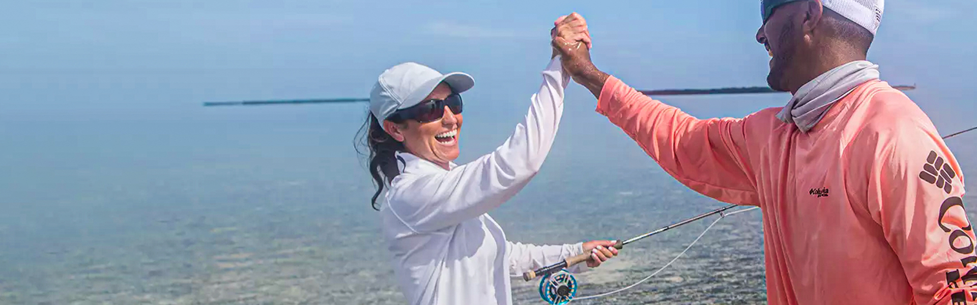 Two people high-fiving and laughing while standing in shallow water