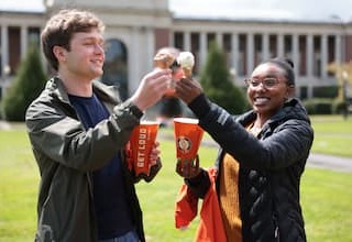 Two students during Dam Proud Day 2022 cheering with icecream cones outside on a sunny day