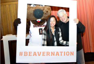 Beaver family members, including father and daughter, taking a photo with Benny at OSU