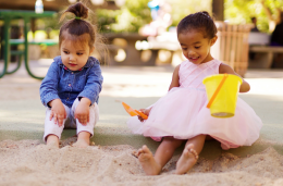 Two children play in sandbox outside