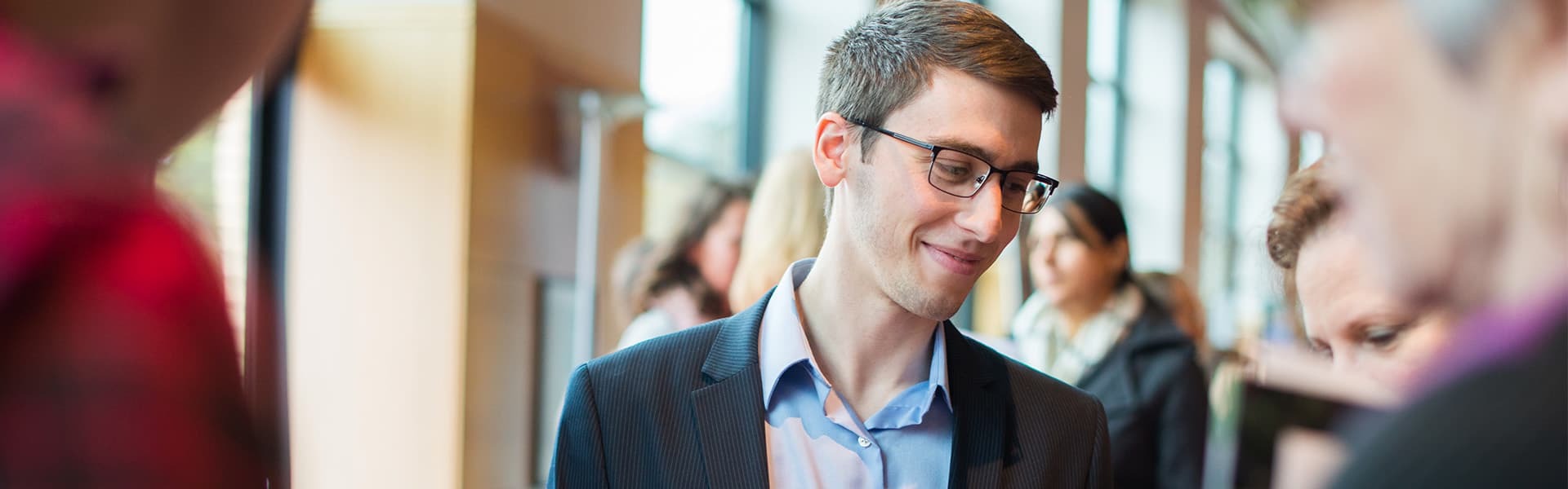 senior at OSU with a name tag and wearing proffesional clothing, he is smiling while interacting with OSU Alumni