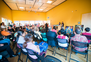 A group sitting and listening to two speakers.