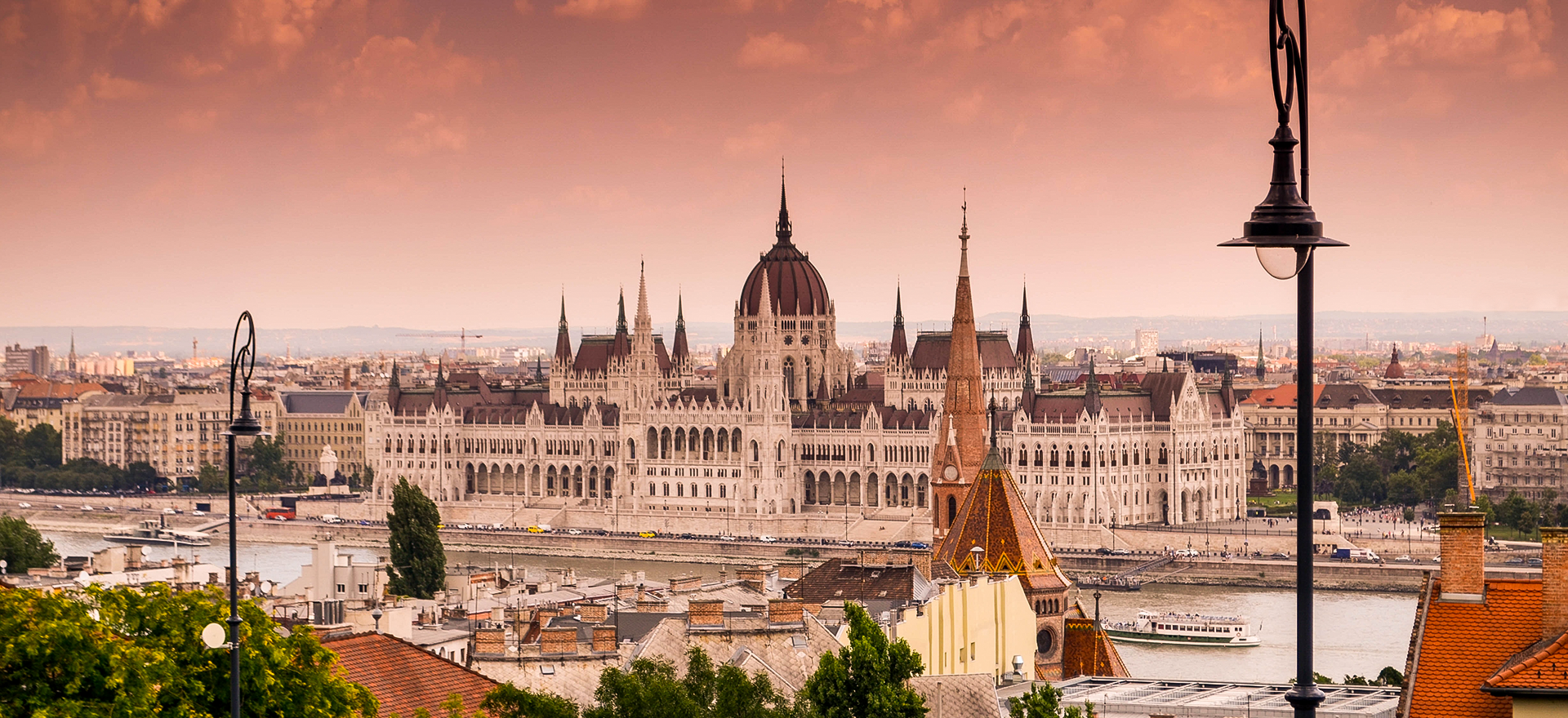 Budapest, Hungary at sunset. A white cathedral building along a river.