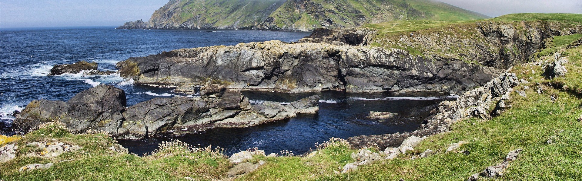 Shetland Isles with rocking coast, blue waters and blue skies with incoming cloud coming in