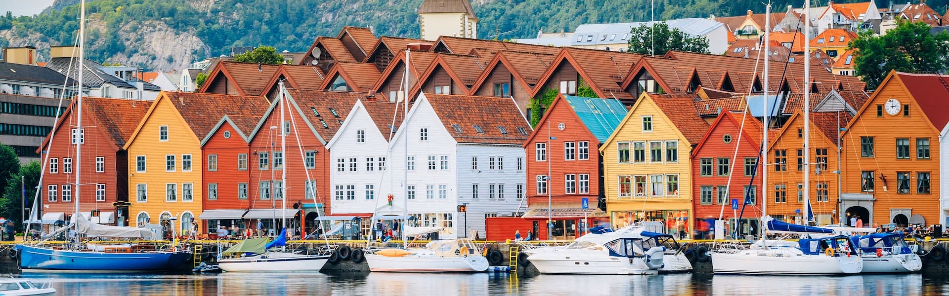 Bergen's colorful coastal buildings by the water with sailboats and mountains in the background