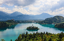 Landscape of Lake Bled with an island in the middle which has buildings, background includes more mountains