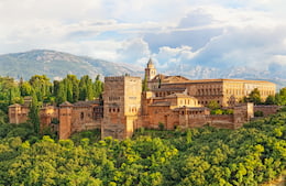 Alhambra palace in Spain, with green treea and mountains in the background