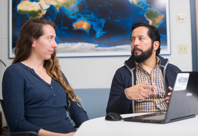 Daniel Palacios sitting at a table speaking with a women at work