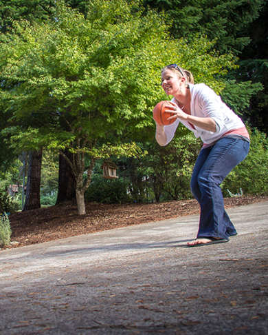 mother and daughter throwing a children's basketball back and forth outside