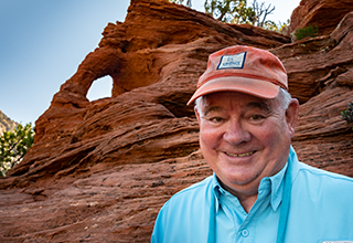 Chuck Armstrong headshot while outdoors with rock formation behind him