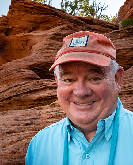 Chuck Armstrong headshot while outdoors with rock formation behind him