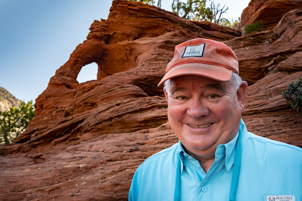 Chuck Armstrong headshot while outdoors with rock formation behind him