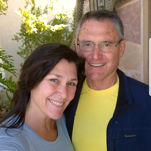 Bob and Kristin Nehler. Bob has a yellow shirt, navy jacket and glasses while Kristin has a light blue shirt and brown hair. They're both smiling for the camera.