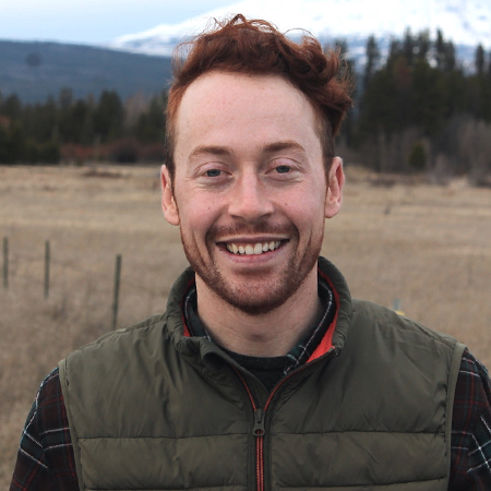 Headshot of Cody Stover. He has red hair and is standing in a field.