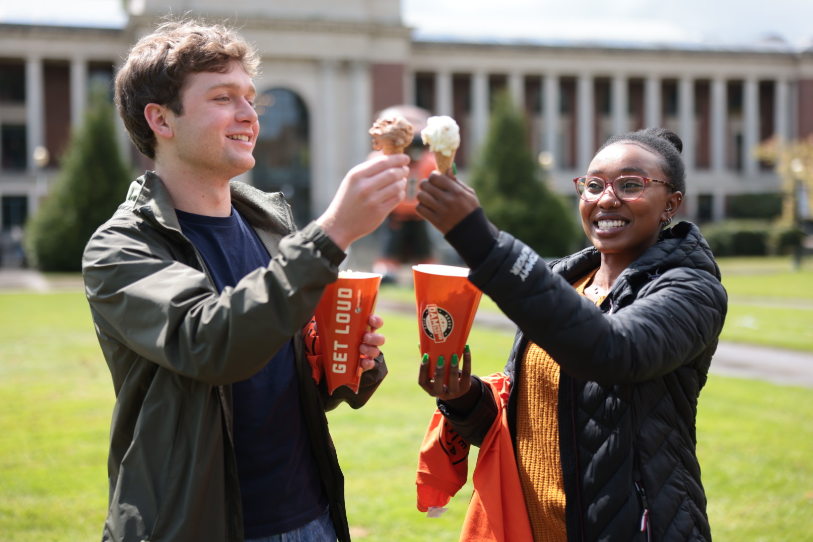 two students cheering eachother with ice cream cones while holding their new OSU swag from Dam Proud Day