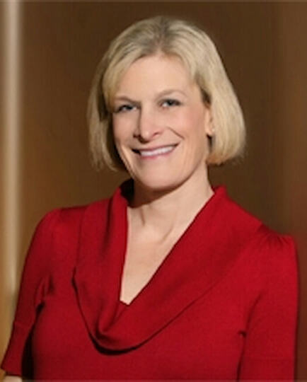 Lydia Mills with blonde hair and a red shirt smiles for her headshot