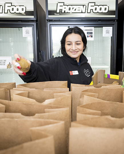 woman putting potato in brown paper bag