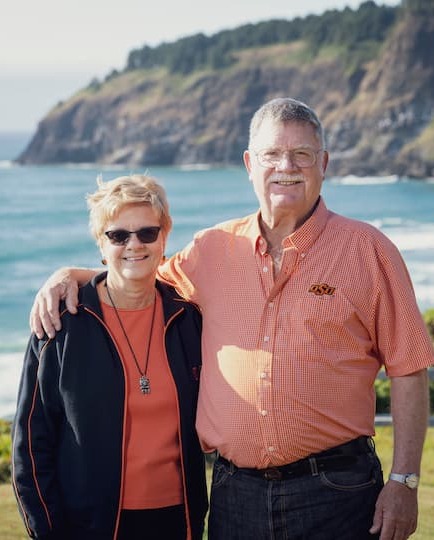 Nancy and Kent Searles outside, backgorund is the beautiful Oregon Coast on a clear day, ocean in the background