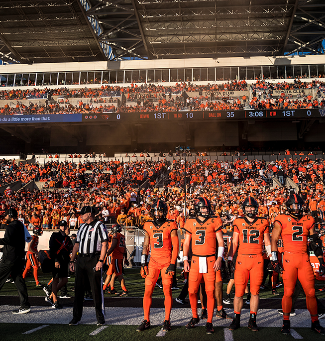 FeaturedEvent_BeaverBowl_Placeholder OSU Beaver football players in orange uniforms standing on the sidelines ready for action