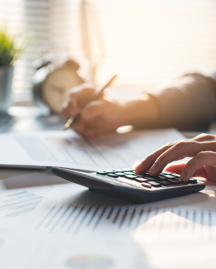 A close-up of a person working at a desk with documents and a calculator.