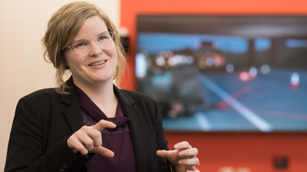A person in business attire speaks while gesturing with their hands.