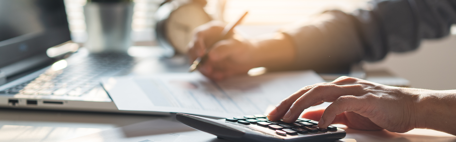 A close-up of a person working at a desk with documents and a calculator.