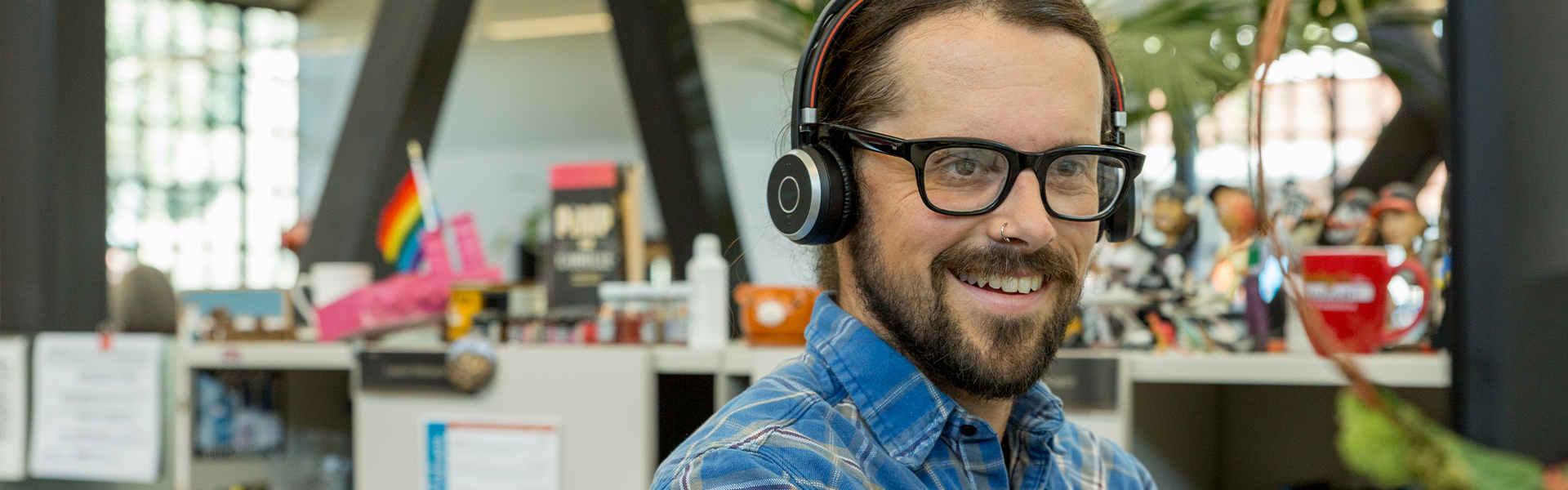 A person with headphones smiling while working at a desk.