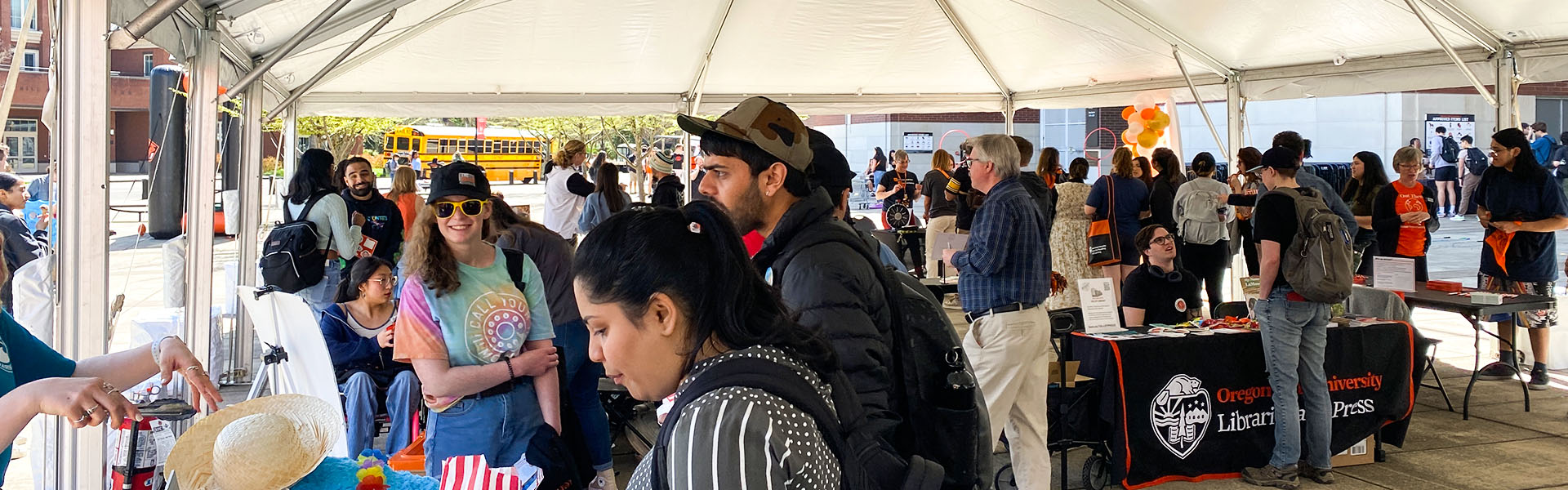 A crowd of people under a large white tent celebrating Dam Proud Day by visiting the various booths of colleges and units.