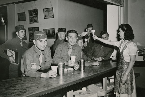 woman serving ice cream to men at counter